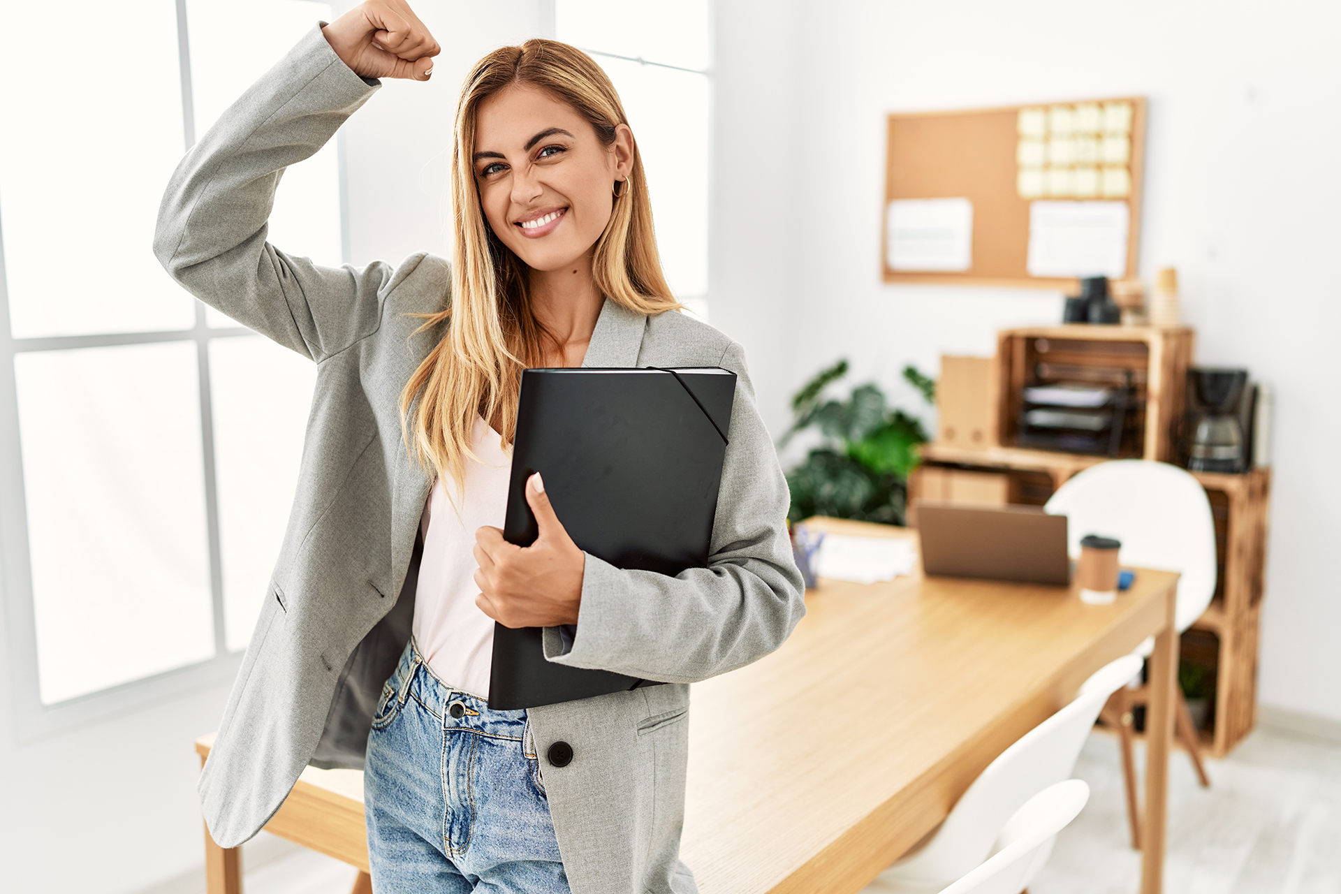 Powerful business woman in office flexing her muscles